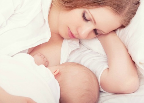 mother feeding breast her baby in the bed. sleeping together